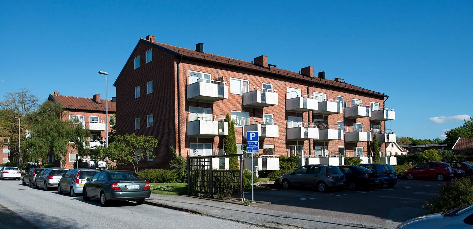 Flerfamiljshus i rött tegel med vita balkonger. 