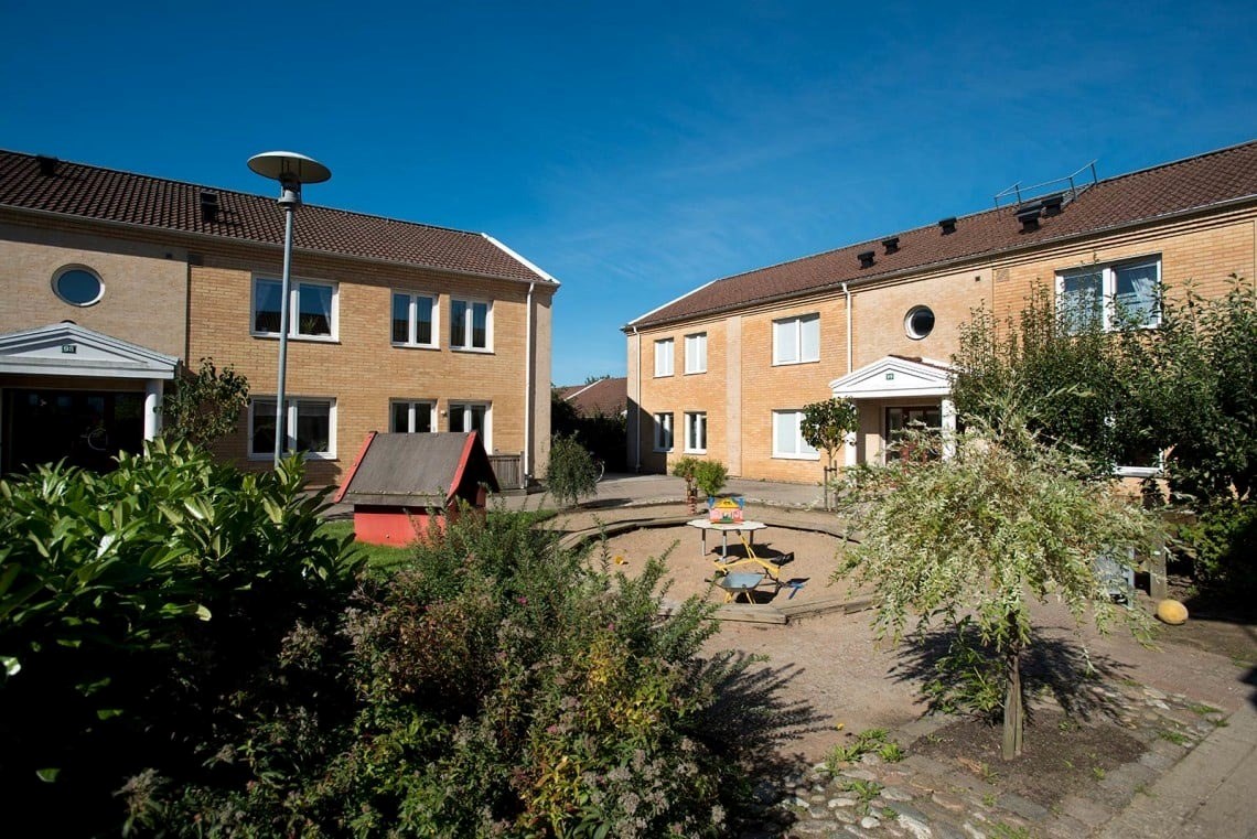 Ett flerfamiljshus i två plan med en lekplats på innergården