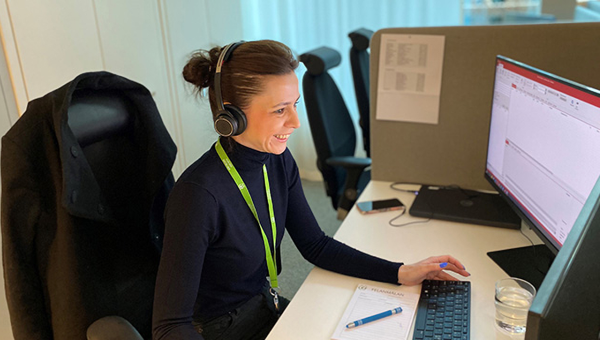 En kundvärd som sitter vid en dator och tar emot ett telefonsamtal från en hyresgäst. 