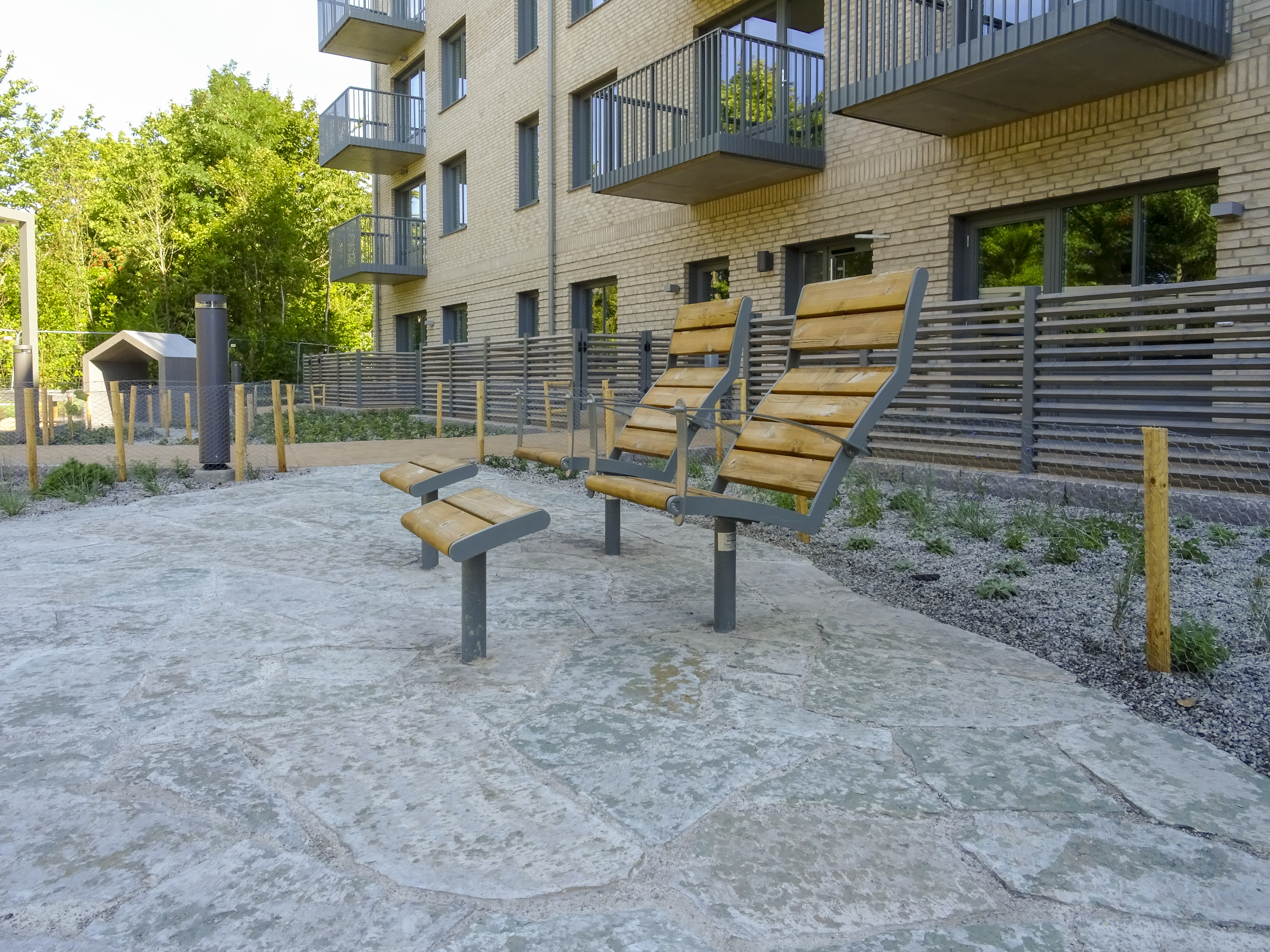 Två fasta solstolar på innergården. I bakgrunden ser man husväggen på fyravåningshuset.