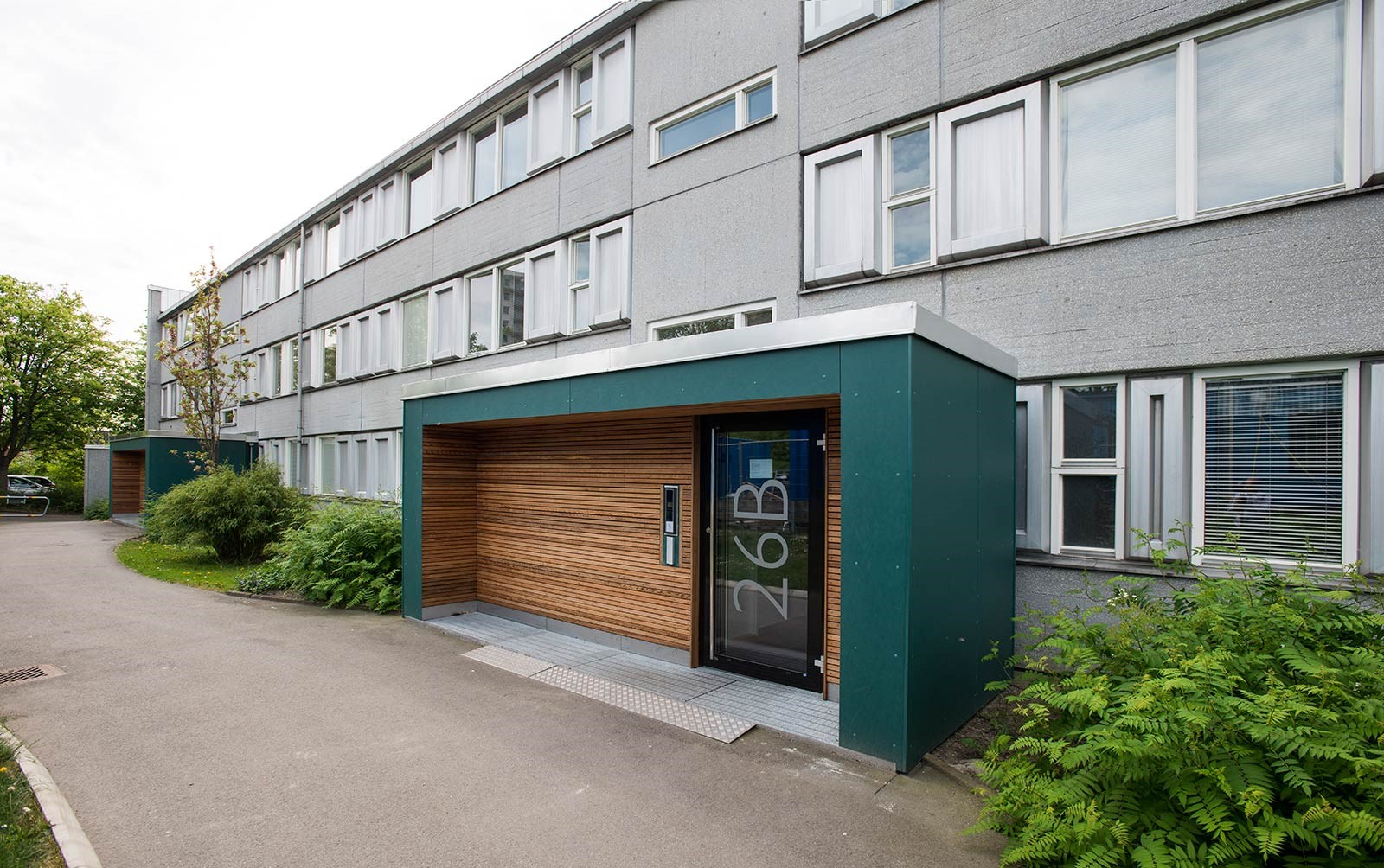 Ingång till ett grått 3-våningshus.