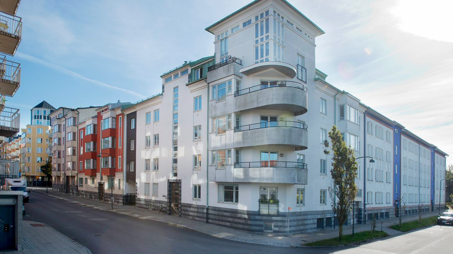 exeteriören av huset för seniorboendet Russinet. Det visar hur huset ligger i ett gathörn. Vit fasade, balkonger med zinkfärgade räcken