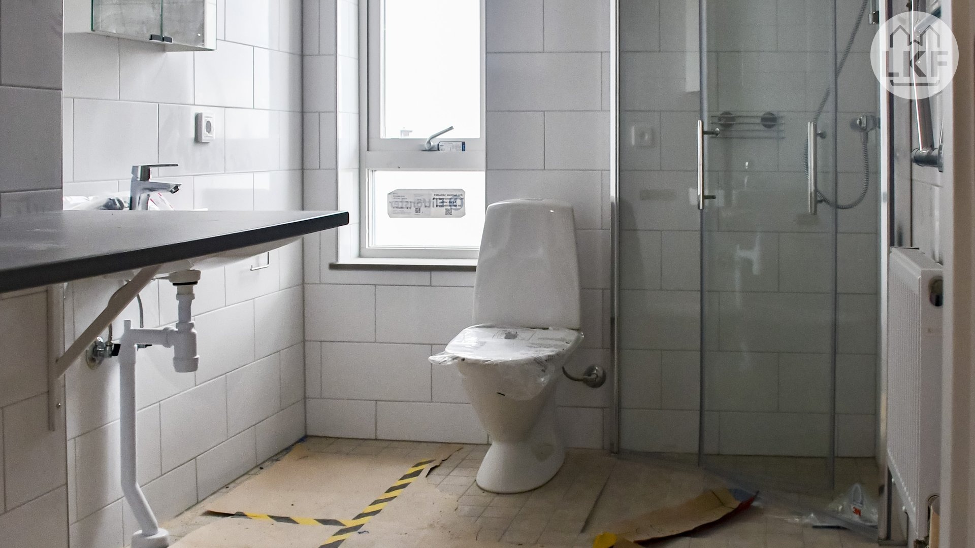 Ett modernt badrum med helkaklade väggar, duschhörna och plats för tvättmaskin