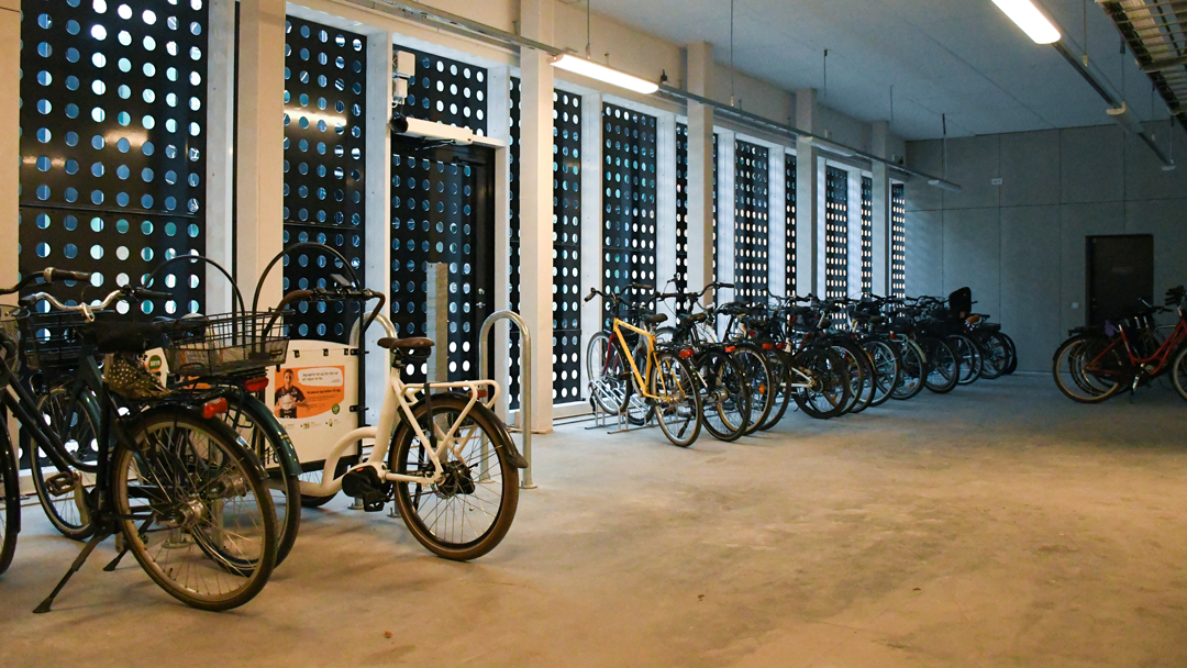 Cykelrummet på Skymningen med parkerade cyklar. Man anar innergården via små hål i den grå plåtväggen