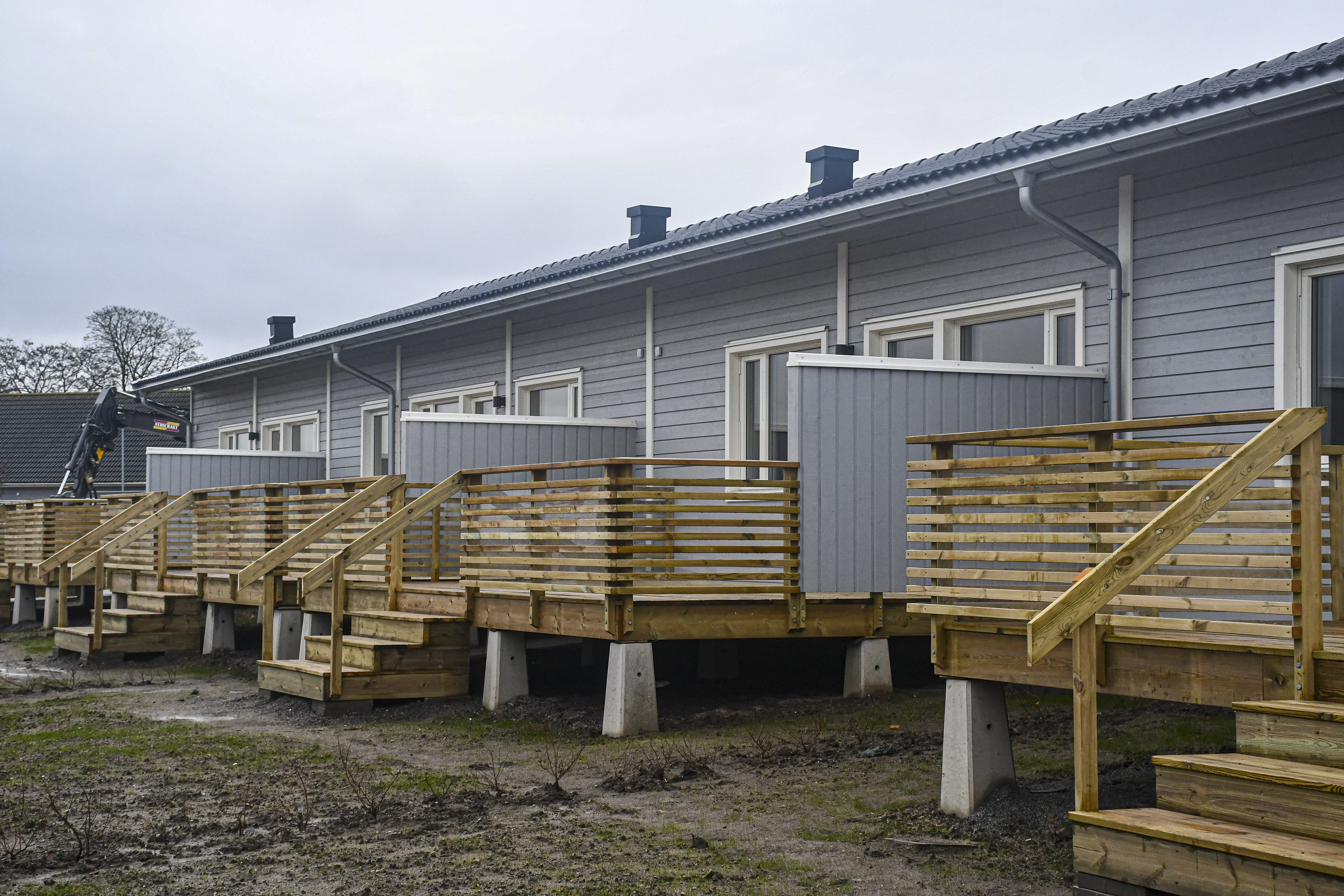 Exteriör bild från Kuylenstjerna. Ljusgråa marklägenheter med utplatser på baksidan och veranda med förråd på framsidan