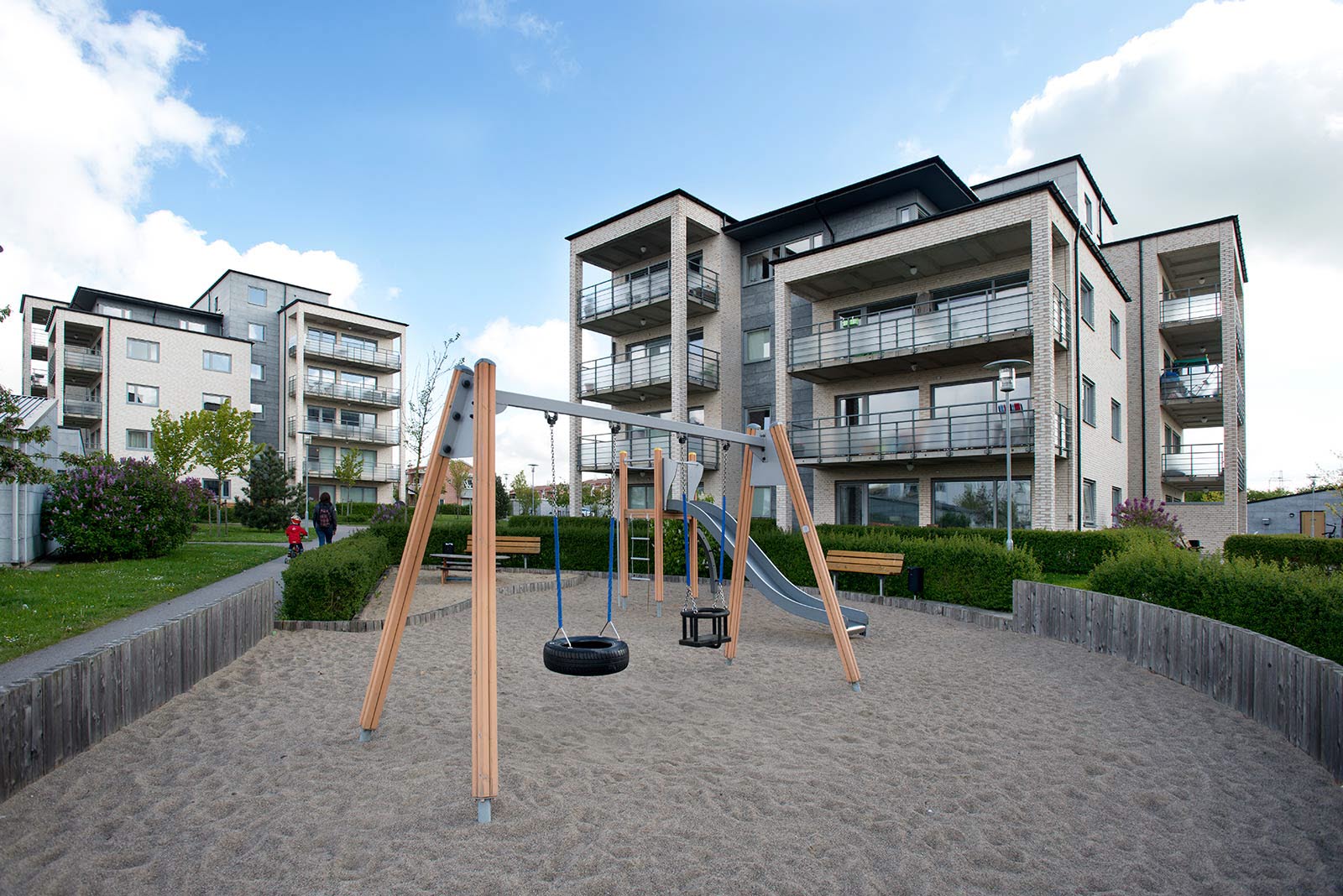 Lekplats med sandlåda och gungor framför flerfamiljshusen i Snäckan