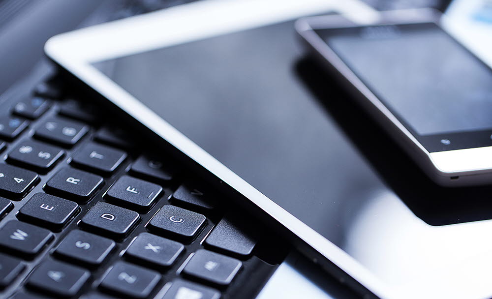 Bild på ett tangentbord, en padda och en mobiltelefon.